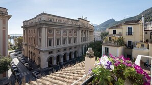 A historic building with classical architecture, a courtyard, and a view of the sea.
