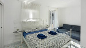 A bedroom with a bed, bedside table, and a sofa.
