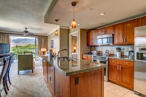 Una cocina moderna con armarios de madera, encimera de granito y electrodomésticos de acero inoxidable.