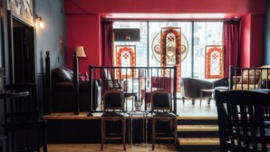 A cozy interior with a red wall, wooden flooring, and a seating area with two chairs and a table. - Swedetown European Style Hostel (Duluth)