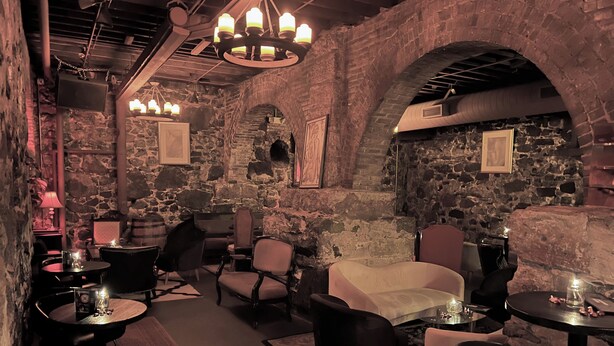 A cozy interior with stone walls, wooden tables, and comfortable seating. - Swedetown European Style Hostel (Duluth)
