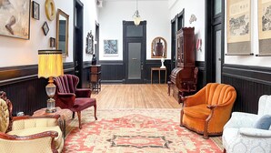A room with a patterned carpet, wooden furniture, and artwork on the walls. - Swedetown European Style Hostel (Duluth)