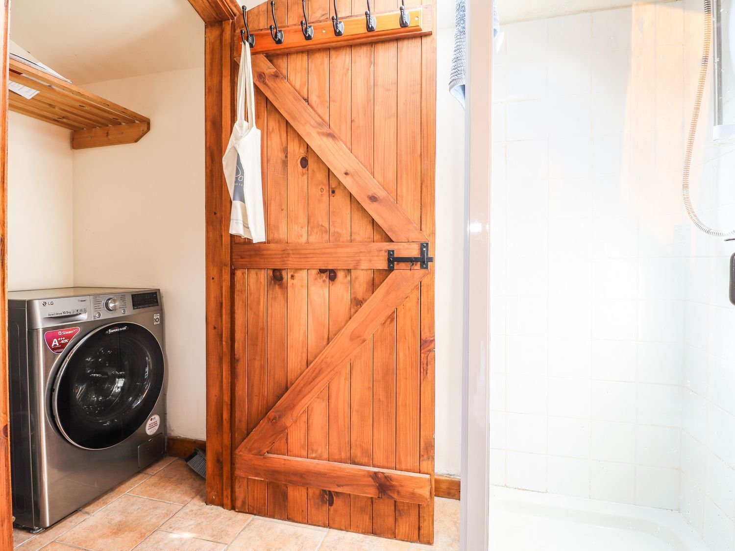 Un área de lavandería con lavadora y una puerta de madera.