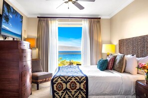 A hotel room with a bed, a chair, a dresser, a television, and a view of the ocean. - Honua Kai | Ocean View 6 BR, Sleeps 18 | Car Incl. w/ 6+ Nights | HKK ML-1442 by KBM (Lahaina)