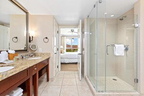 A modern bathroom with a glass-enclosed shower, a vanity with a granite countertop, and a large mirror. - Honua Kai | Ocean View 6 BR, Sleeps 18 | Car Incl. w/ 6+ Nights | HKK ML-1442 by KBM (Lahaina)