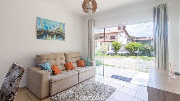 A modern living room with a beige sofa, a painting, and a view of a courtyard. - Apt w/ Barbecue 500m From the Beach Pbr1003 (Porto Seguro)