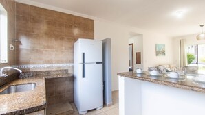A modern kitchen with a built-in refrigerator, granite countertops, and a large island with seating. - Apt w/ Barbecue 500m From the Beach Pbr1003 (Porto Seguro)