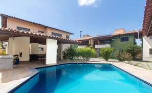 A swimming pool with tiled edges, surrounded by a covered patio area, and adjacent buildings with tiled roofs. - Apt w/ Barbecue 500m From the Beach Pbr1003 (Porto Seguro)
