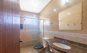 Een moderne badkamer met een douchecabine van glas, een toilet en een wastafel met een granieten aanrecht.