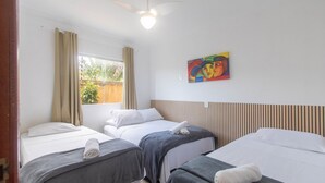 A hotel room with three beds, a ceiling fan, a window with curtains, and a painting on the wall. - Apt w/ Barbecue 500m From the Beach Pbr1003 (Porto Seguro)