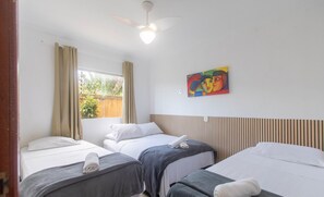 A hotel room with three beds, a ceiling fan, a window with curtains, and a painting on the wall. - Apt w/ Barbecue 500m From the Beach Pbr1003 (Porto Seguro)
