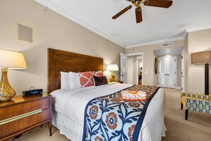 Una habitación de hotel con cama, mesita de noche, lámpara y ventilador de techo.