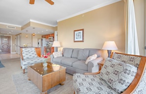 A living room with a sofa, two armchairs, a coffee table, and a kitchen in the background. - Honua Kai | Ocean View 8 BR, Sleeps 22 | Car Incl. w/ 6+ Nights | HKK ML-1457 by KBM (Lahaina)
