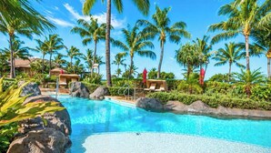 Ein Hotelpool mit Palmen, Liegestühlen und blauem Himmel.