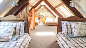 Un dormitorio acogedor en el ático con dos camas, una pared de piedra, vigas de madera y vistas a una habitación rústica.