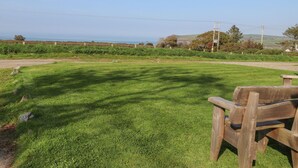 Un campo cubierto de hierba con un banco de madera y vista al mar.