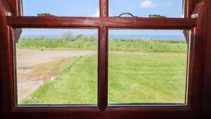 Una ventana con vista a un campo cubierto de hierba y un sendero de tierra.