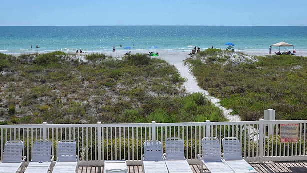 A beach view with a white fence, lounge chairs, and a sign indicating no diving. - Beachfront condo with washer dryer pool and hot tub dog friendly (Indian Rocks Beach)