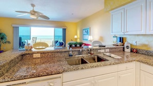A kitchen with granite countertops, a double sink, and white cabinets. - Beachfront condo with washer dryer pool and hot tub dog friendly (Indian Rocks Beach)