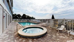 Ett poolområde på taket med en bubbelpool, solstolar och en skylt som beskriver reglerna för spa-anläggningen.