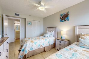 A bedroom with two beds, a ceiling fan, a nightstand, and a wall with a turtle painting. - Bright and recently redone condo hot tub pool and tennis direct beach access (Indian Rocks Beach)