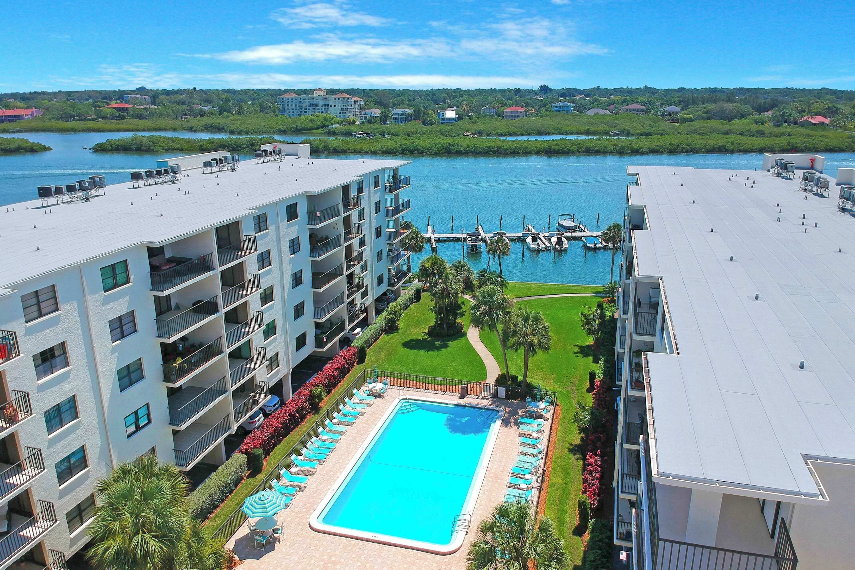 A hotel with a rooftop pool, multiple balconies, and a view of a marina.