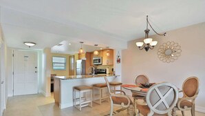 Una cocina moderna con una isla central, taburetes de bar y una mesa de comedor con sillas.