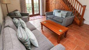 A living room with a sofa, a wooden coffee table, and a staircase. - Ty Fferm (Newport)