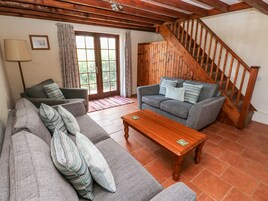 Una sala de estar con un sofá, una mesa de centro de madera y una escalera.