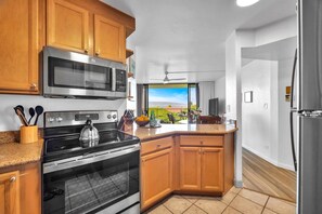 Una cocina con armarios de madera, electrodomésticos de acero inoxidable y vistas a un paisaje verde.