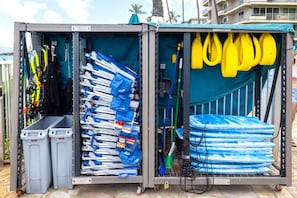 A storage unit with various cleaning supplies, including brooms, mops, and buckets.