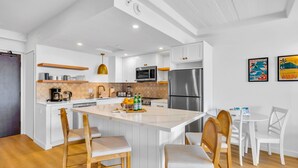 Une cuisine moderne avec des meubles blancs, un îlot central, des chaises en bois et une table à manger.