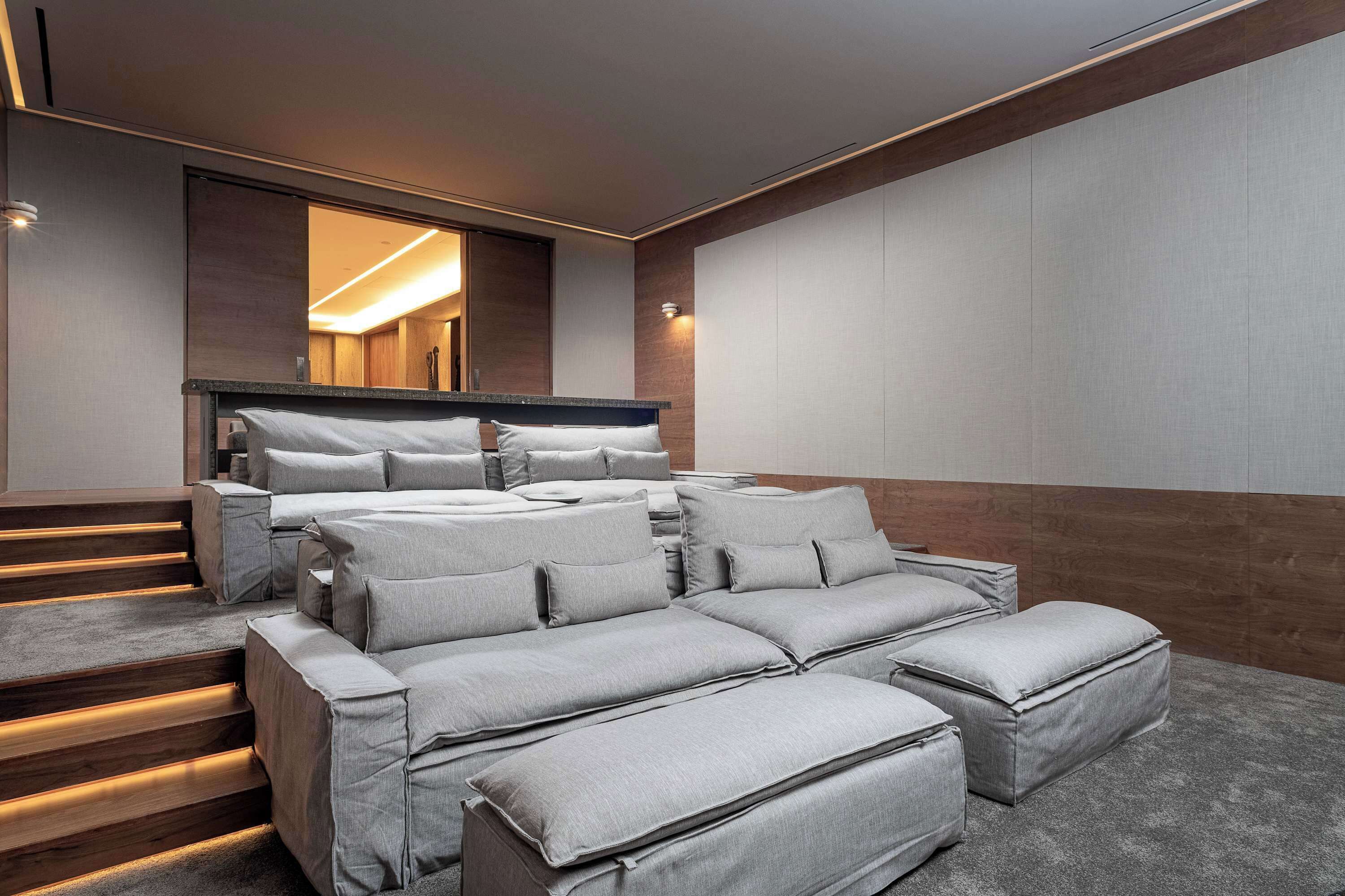 A modern bedroom with a large bed, multiple seating areas, and a staircase.