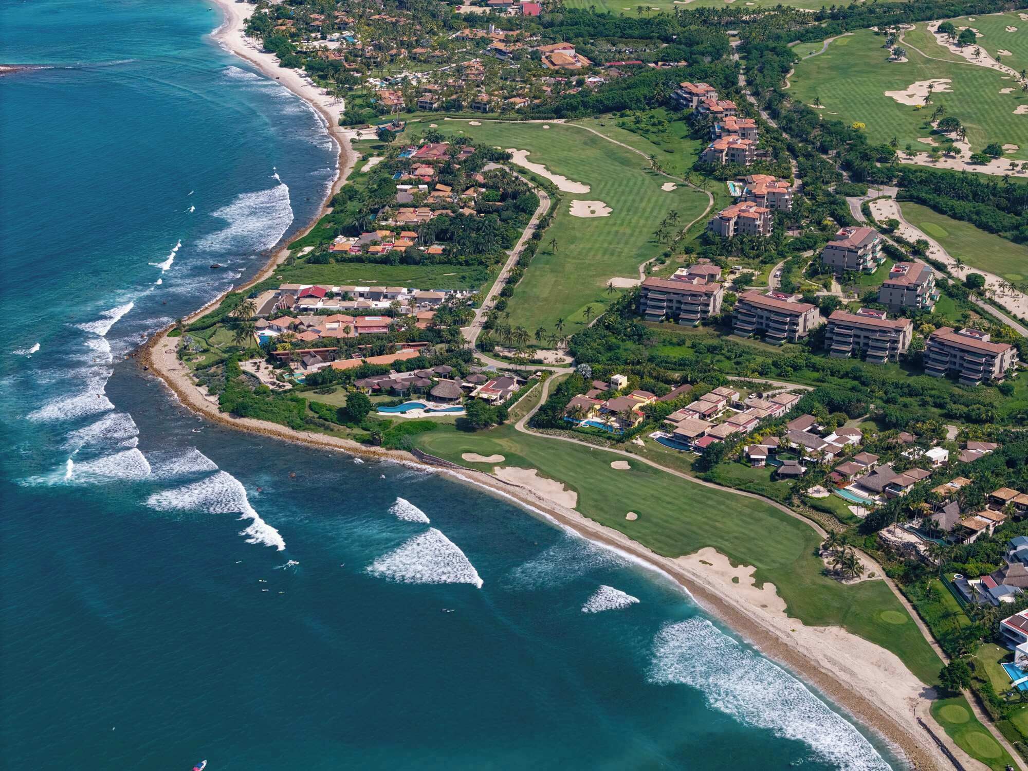 Eine Vogelperspektive eines Küstenresorts mit Strandhäusern, Golfplätzen und einem Schwimmbad.