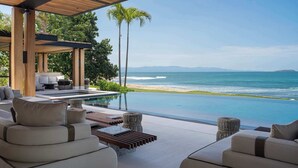 A modern outdoor lounge area with a pool overlooking a beach and ocean.