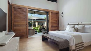 A modern bedroom with a large bed, wooden paneling, a bench, and a view of the outdoors.