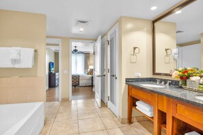 Un baño de hotel con bañera, dos lavamanos, un espejo grande y cabina de ducha.