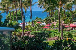 Un resort tropical con palmeras, vista al océano y edificios con techos rojos.
