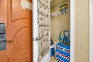 Habitació amb una porta, un moble penjat a la paret, un llit amb un estovat de colors i una estant amb diversos objectes.