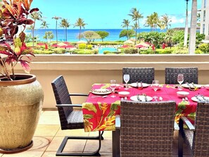 Comedor con mesa dispuesta para cuatro, con vista a una piscina y al océano.