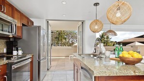 A modern kitchen with stainless steel appliances, a granite countertop, and a view of the outdoors.