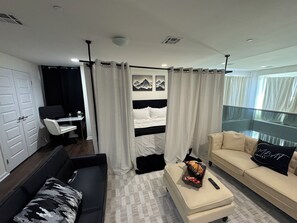 A modern hotel room with a bed, a sofa, a desk, and a balcony.