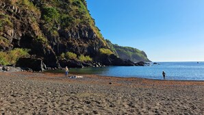A beach with rocky terrain and a clear view of the ocean.