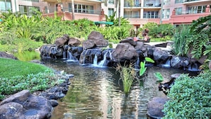 Un jardin aménagé avec une petite cascade, des rochers et une végétation luxuriante.