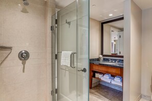 Une salle de bain moderne avec une douche à parois de verre, un meuble-lavabo doté d’un plan de travail en marbre et un grand miroir.