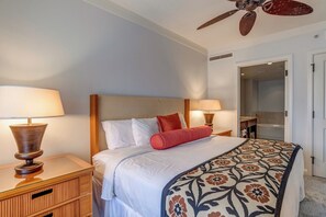 A hotel room with a bed, two bedside lamps, a ceiling fan, a bathroom visible through an open door, and a patterned throw blanket. - 2 Honua Kai Villas | Ocean Front | Sleeps 12 | Free Car w/ 6+ Nights | ML-1790 (Lahaina)