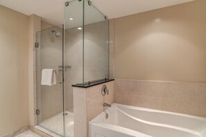 Ein modernes Badezimmer mit einer gläsernen Duschkabine, einer weißen Badewanne und beige gefliesten Wänden.