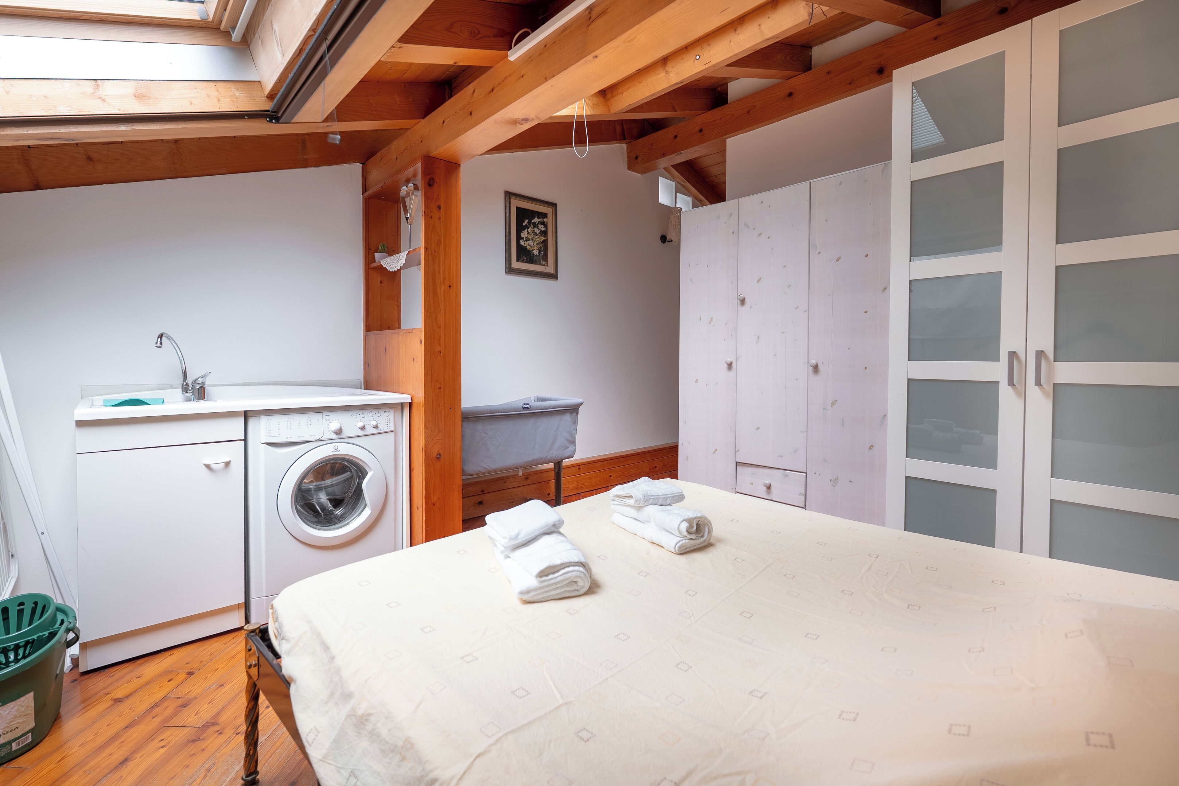 A compact bedroom with a bed, a washing machine, and a small bathroom.