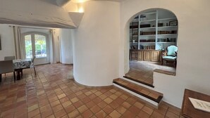 A spacious room with a tiled floor, a dining area with a table and chairs, and a bookshelf in the background. - Countryside villa with swimming pool (Lambesc)
