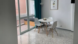 A modern room with a balcony, a dining table with chairs, a framed picture on the wall, and a white floor. - Vacation Studio 'Puerto Centro House' with Balcony and Wi-Fi (Puerto de la Cruz)
